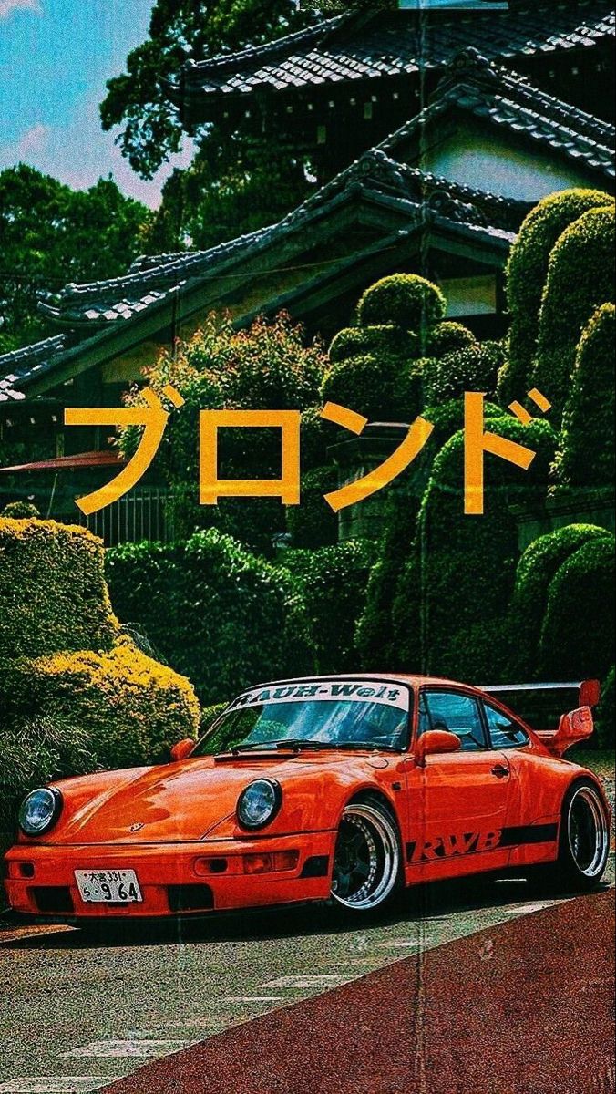 an orange car parked in front of a building with japanese writing on the side of it