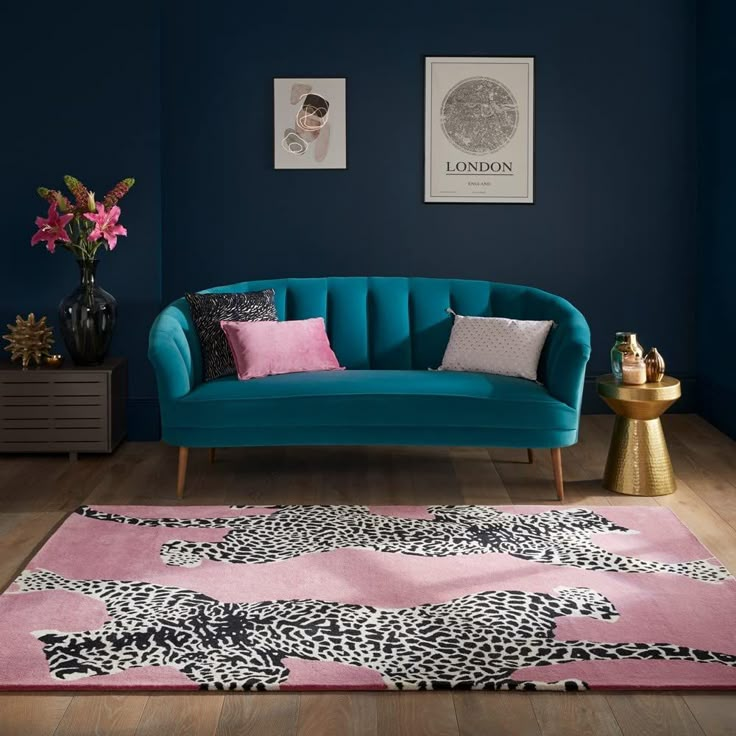 a blue couch sitting on top of a wooden floor next to a pink and black rug