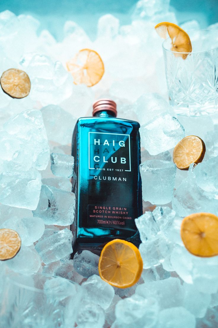 a bottle of haig club sitting on top of ice with lemon slices around it