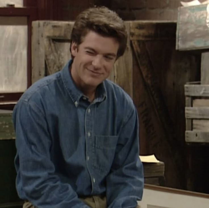 a man sitting on top of a wooden bench