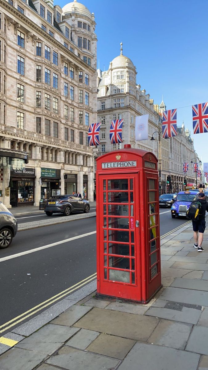 a red phone booth sitting on the side of a road