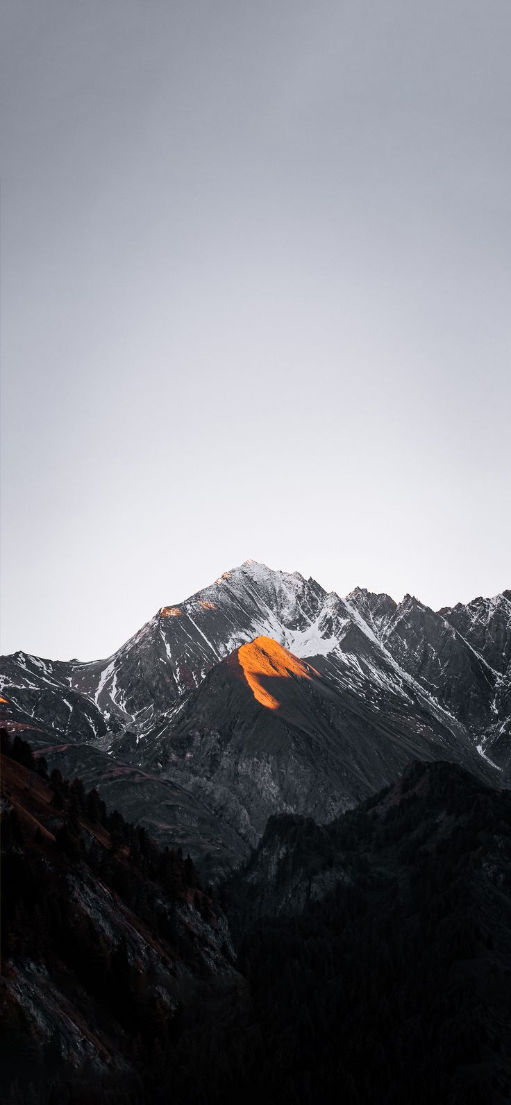 the mountains are covered in snow and orange light