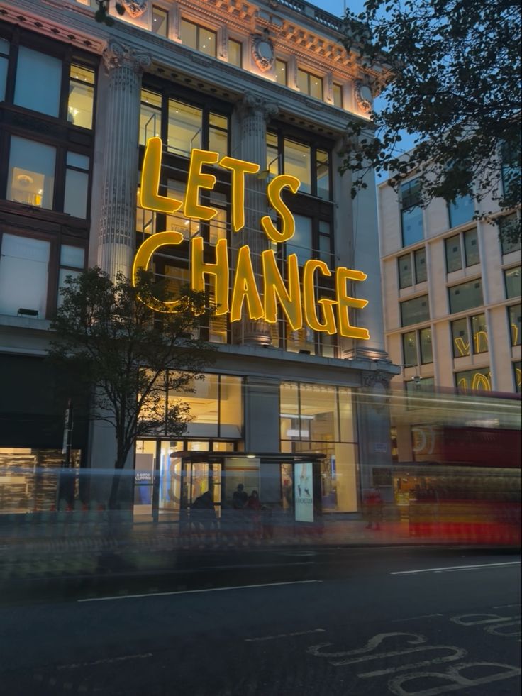 the words let's change are lit up in front of a building