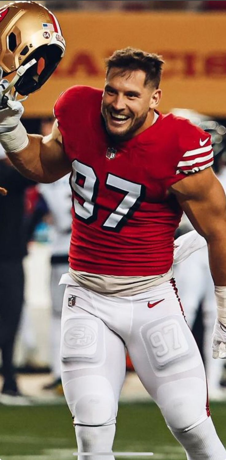 a man holding a football helmet on top of a field