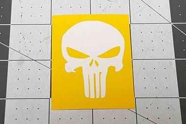 a yellow and white sticker with a skull on it's face in the middle of a tiled floor