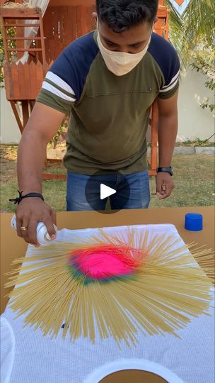 a man in a face mask is making an art project