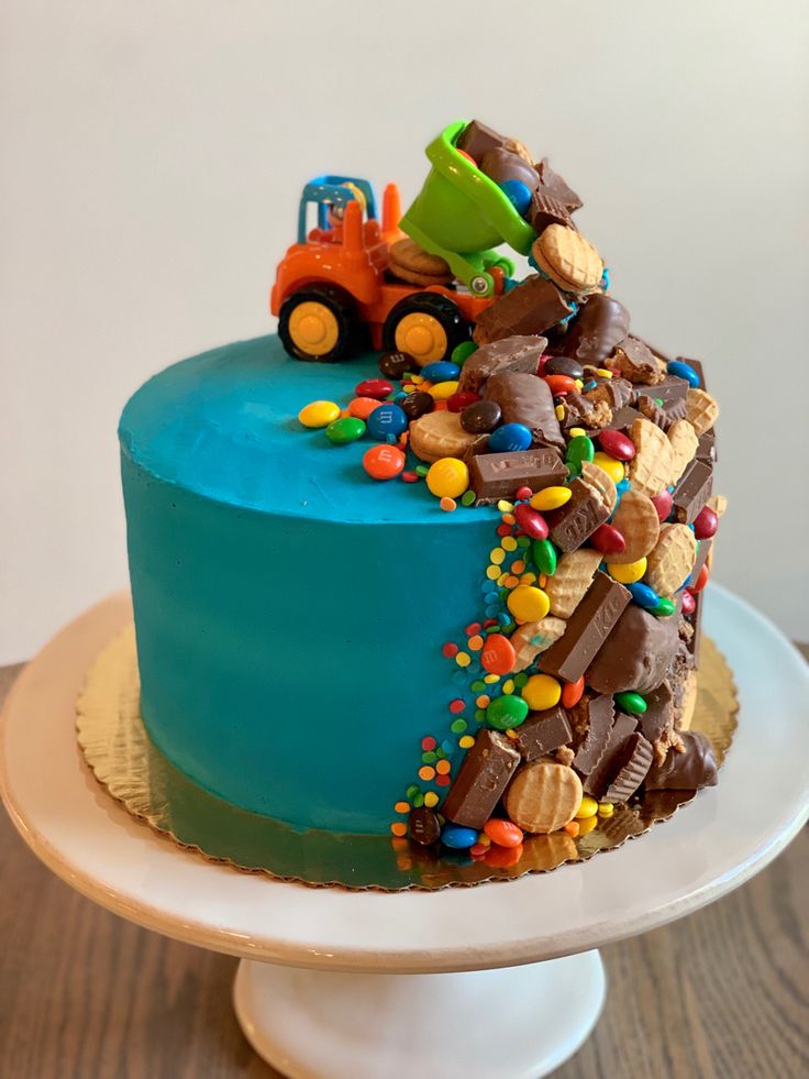 there is a cake that has been decorated with construction vehicles and candy on top of it