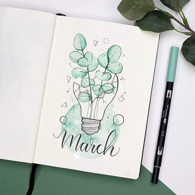 an open notebook with the words march written on it next to a pen and plant