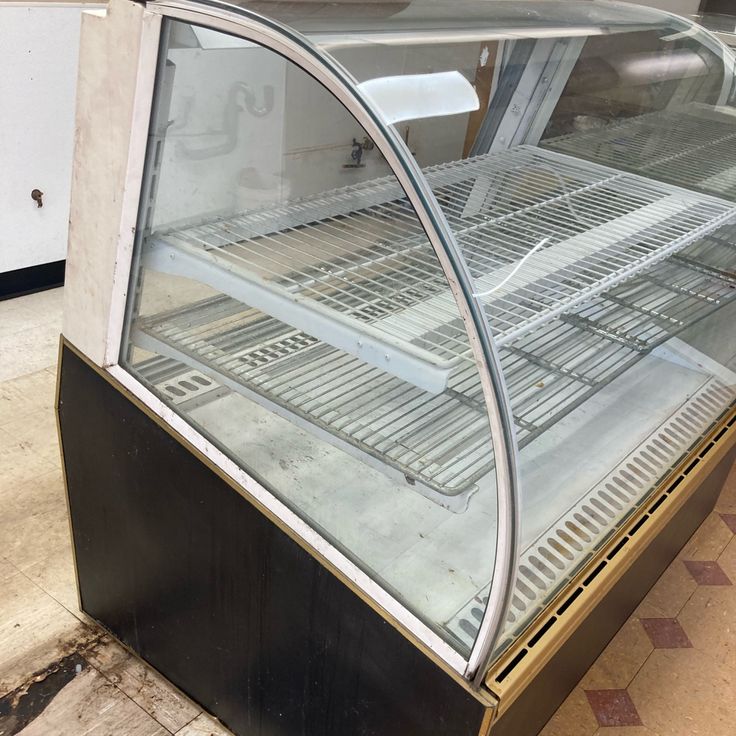 an empty glass display case sitting on the side of a building next to a tiled floor