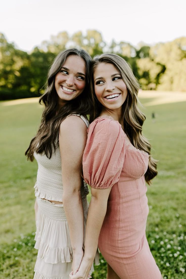 two women standing next to each other in a field