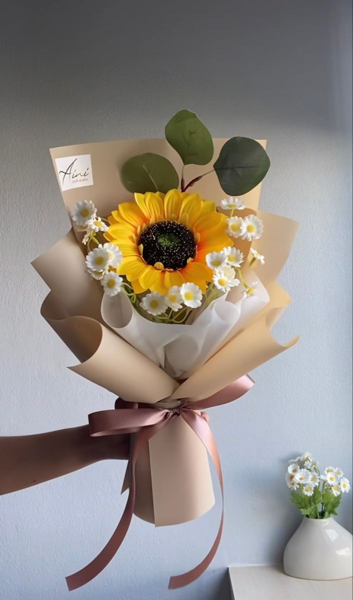 a bouquet of sunflowers and daisies wrapped in brown paper