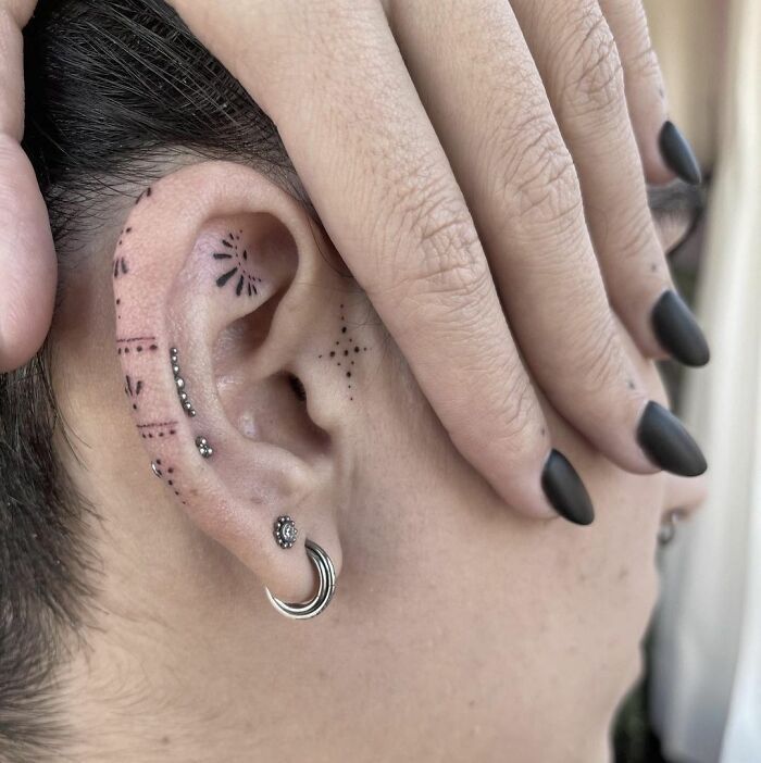 a woman with black nails and piercings on her ear