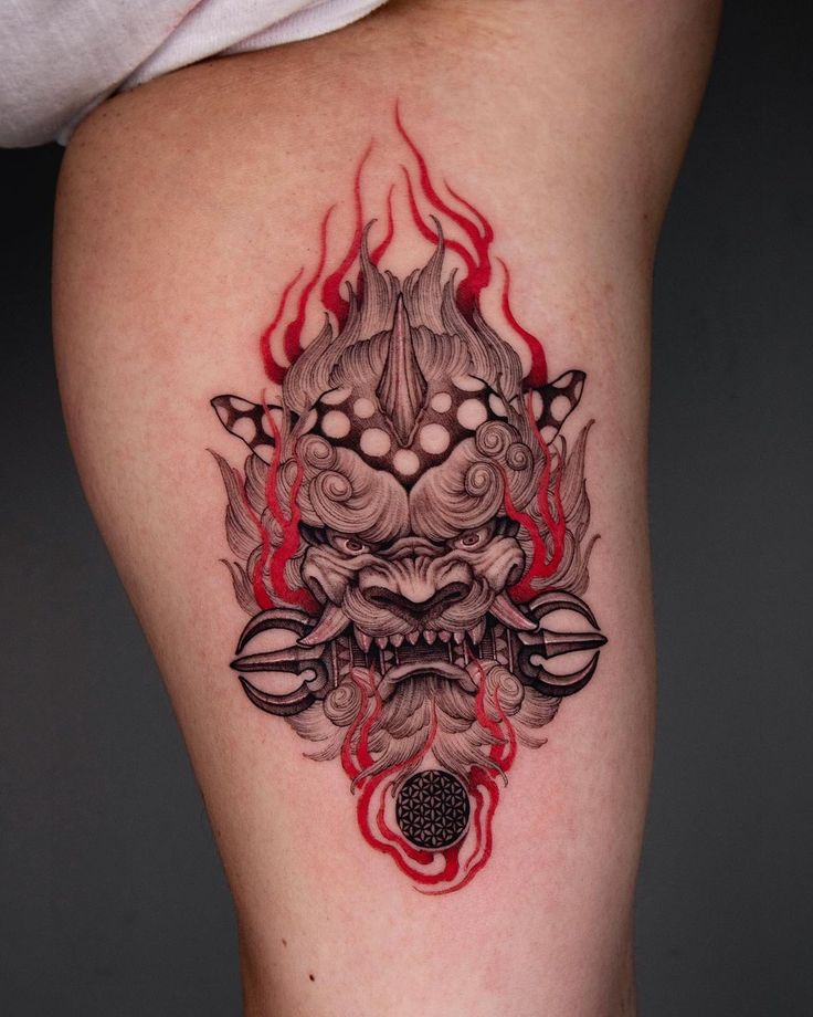 a tattoo on the leg of a woman with red flames around her head and demon face