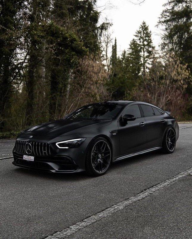 a black mercedes cla parked on the side of the road in front of some trees