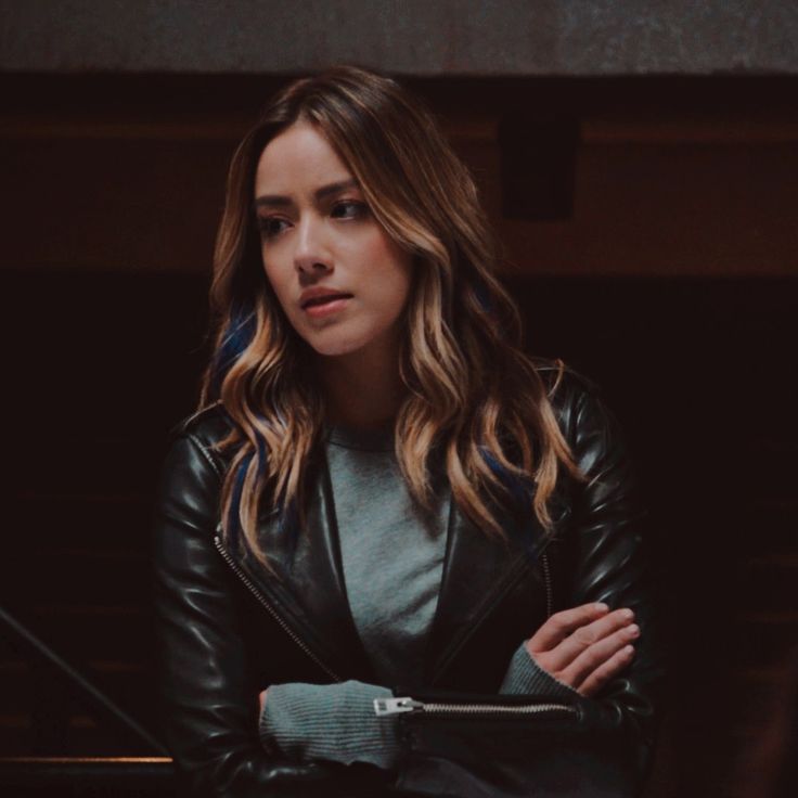 a woman in a black leather jacket is looking at something