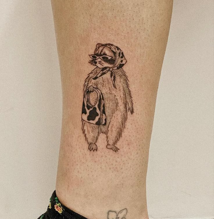 a small raccoon tattoo on the leg of a woman's lower body