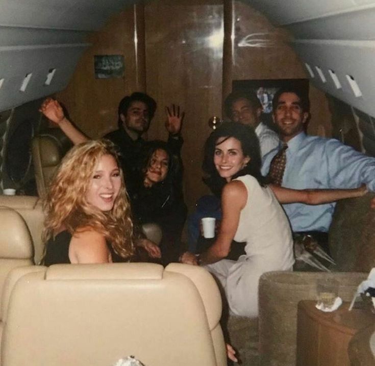 a group of people sitting on top of an airplane next to each other with their arms in the air