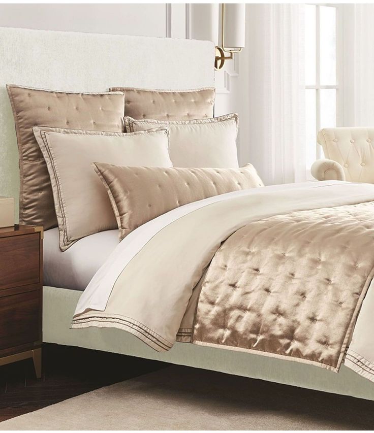 a bed with white and gold comforters in a bedroom