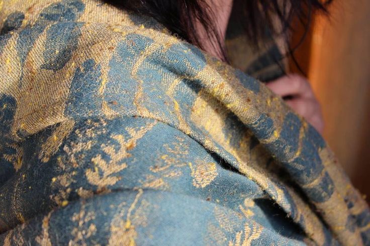 a close up of a person wearing a blue and yellow patterned coat with an animal on it's chest