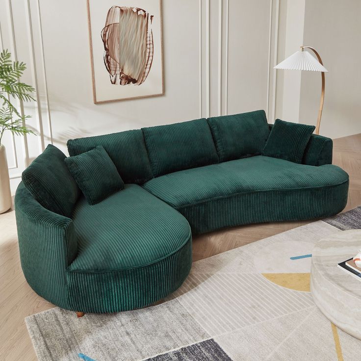 a large green couch sitting on top of a wooden floor next to a white rug