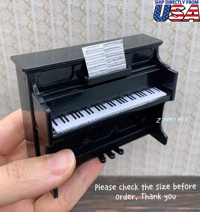 a hand holding a miniature black piano with notes on it's keys and the words please check the size before ordering order, thank you