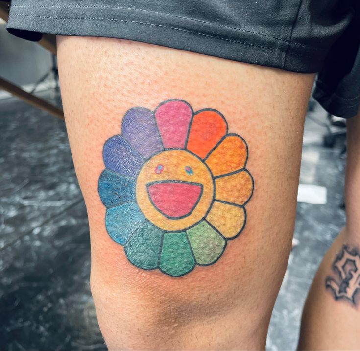 a colorful tattoo on the leg of a woman's thigh with an image of a flower