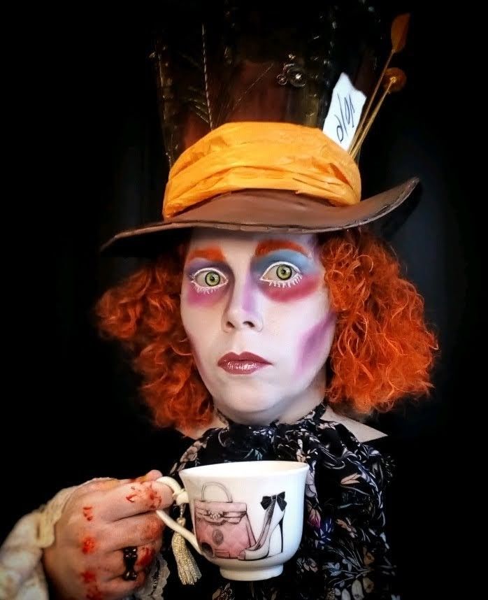 a woman with red hair and makeup holding a cup