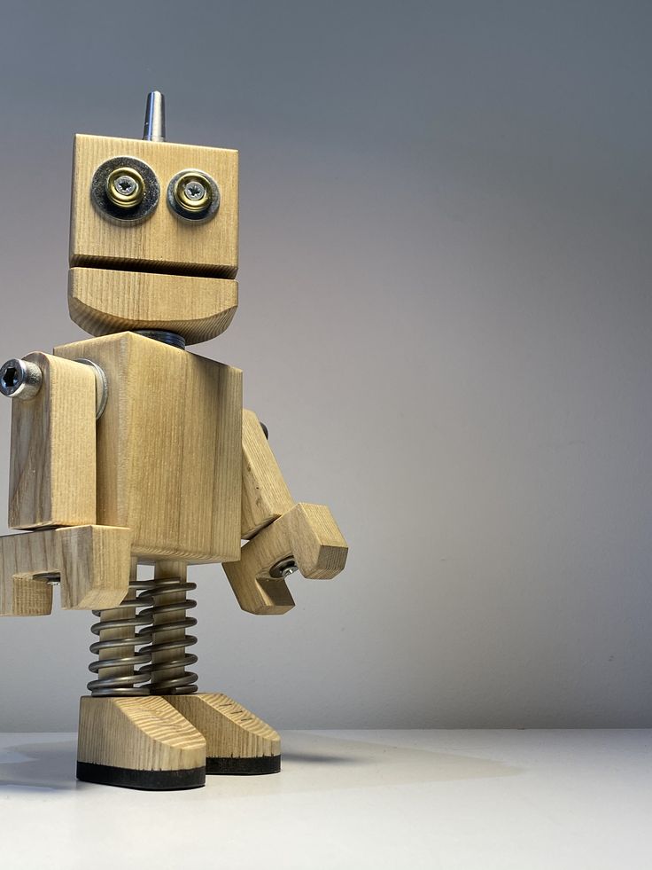 a wooden toy robot standing on top of a table