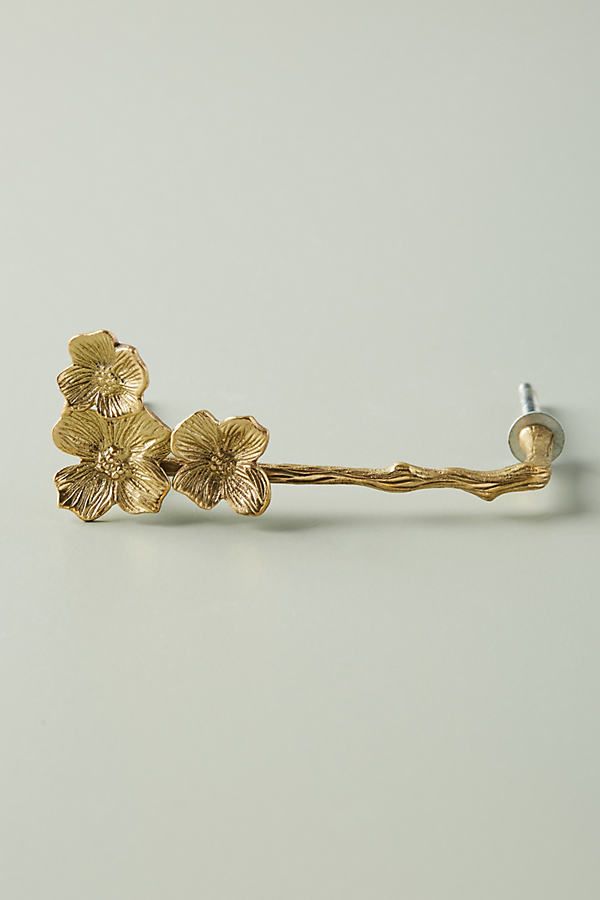 a pair of gold colored flowers on a white surface with a screw in the middle