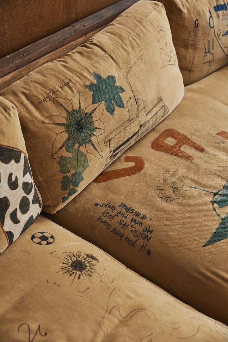 the back of a couch with various pillows on top of it and writing on the cushions