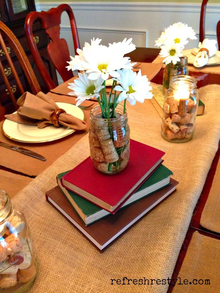 a table topped with books and vases filled with flowers on top of each other