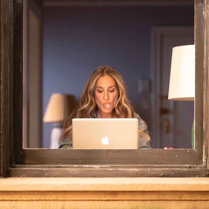 a woman is looking at her laptop in the window