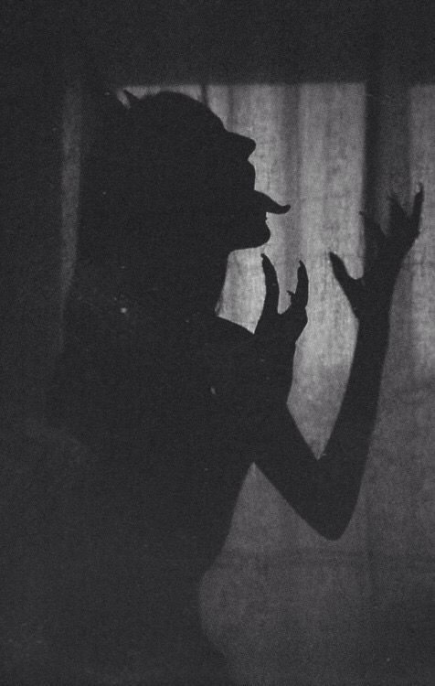 the shadow of a person standing in front of a curtain with their hands raised up