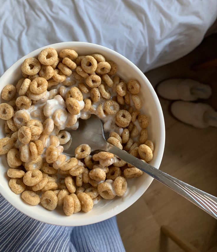 a person holding a bowl of cereal with a spoon in it