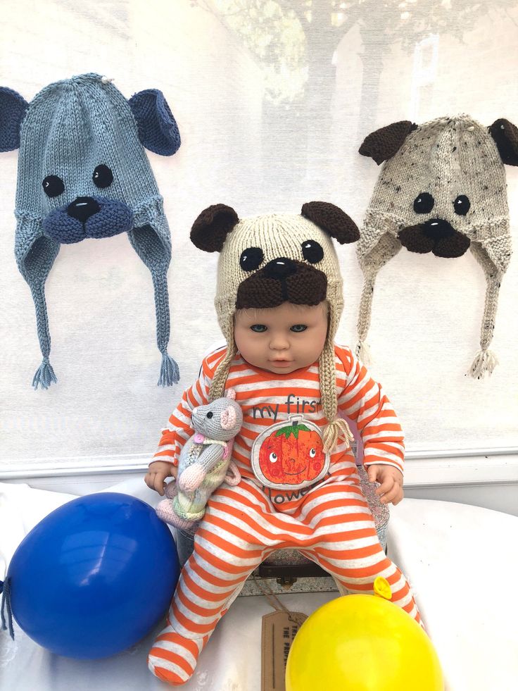 a baby doll sitting on top of a table next to balloons and stuffed animal heads