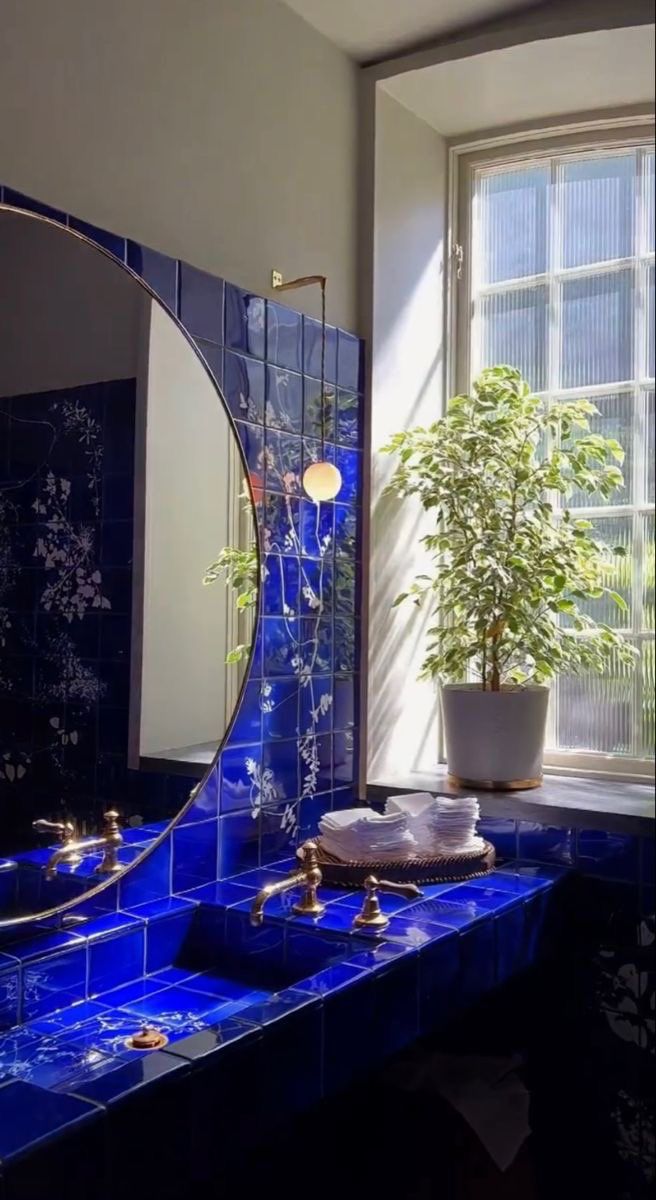 a bathroom with blue tiles and a potted plant on the counter next to it