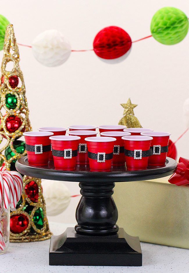 there are many red cups on the cake plate with candy canes in front of them