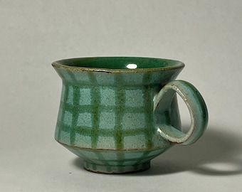 a green and white checkered cup sitting on top of a table