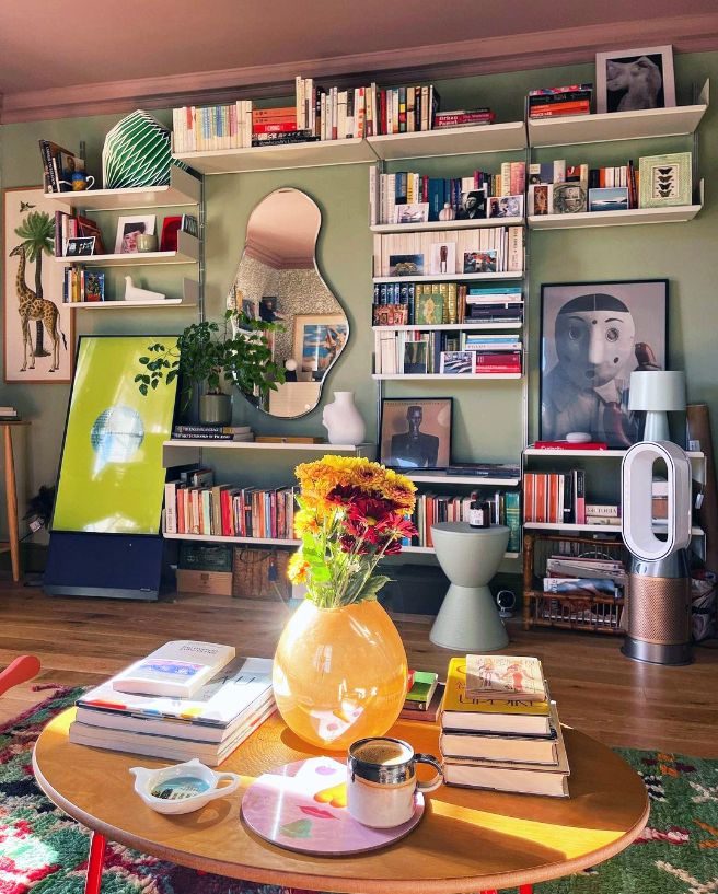 a living room filled with lots of books and flowers on top of a coffee table