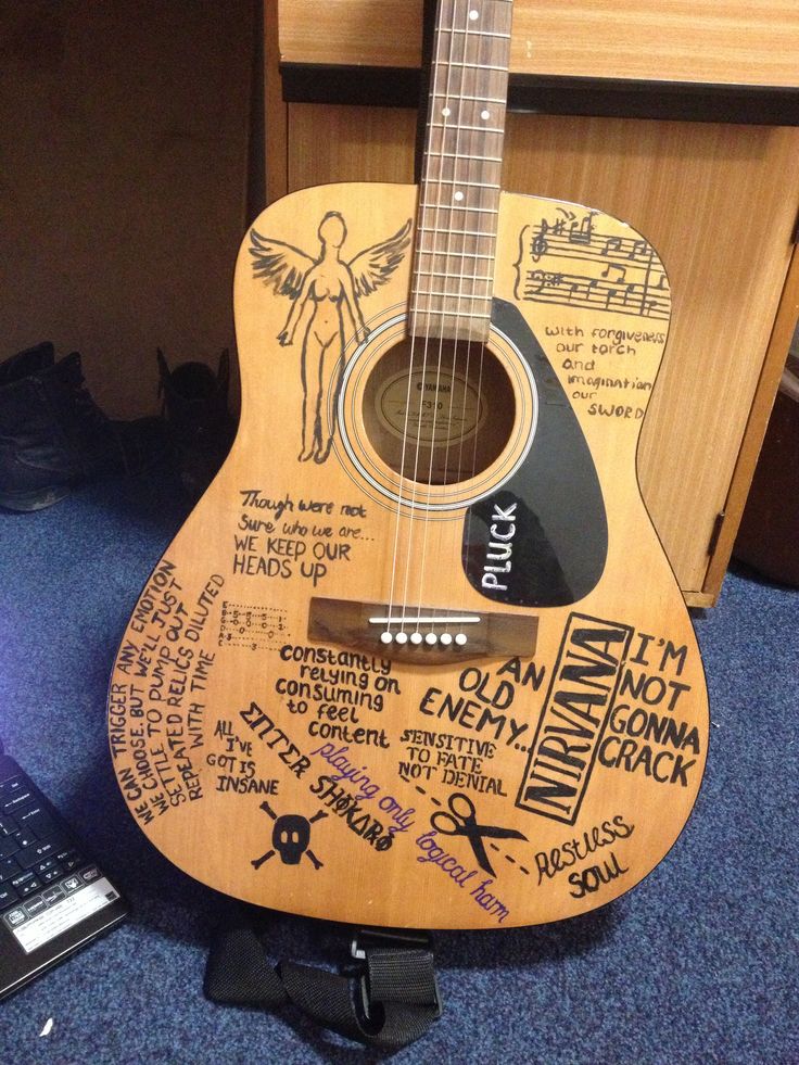 a wooden guitar with writing on it sitting next to a keyboard