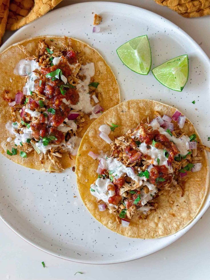 two tacos with toppings on a white plate