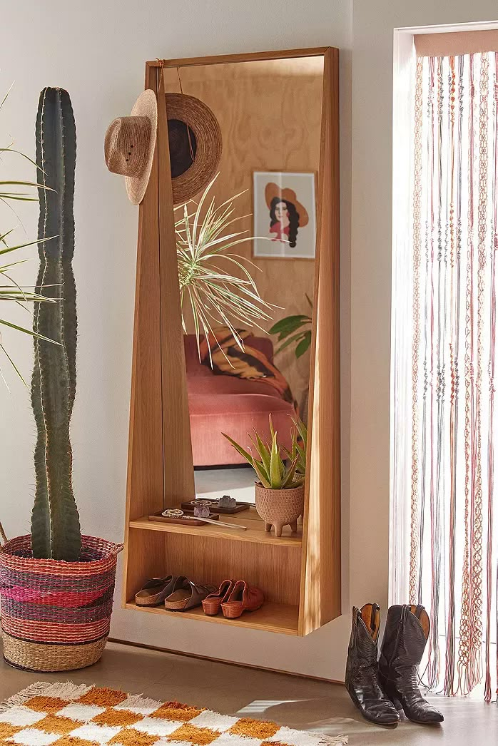 a room with a mirror, potted plant and shoes on the floor