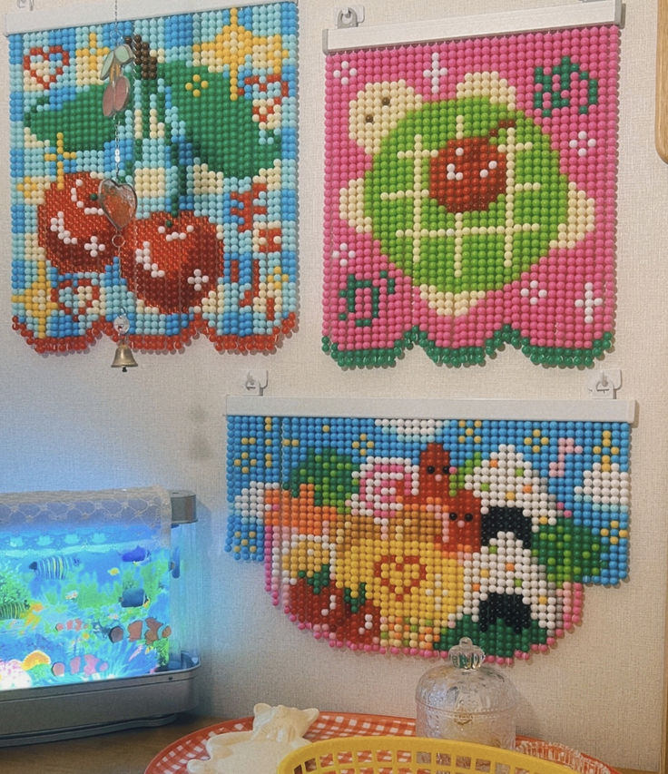 three cross stitch pictures hanging on the wall next to a fish tank