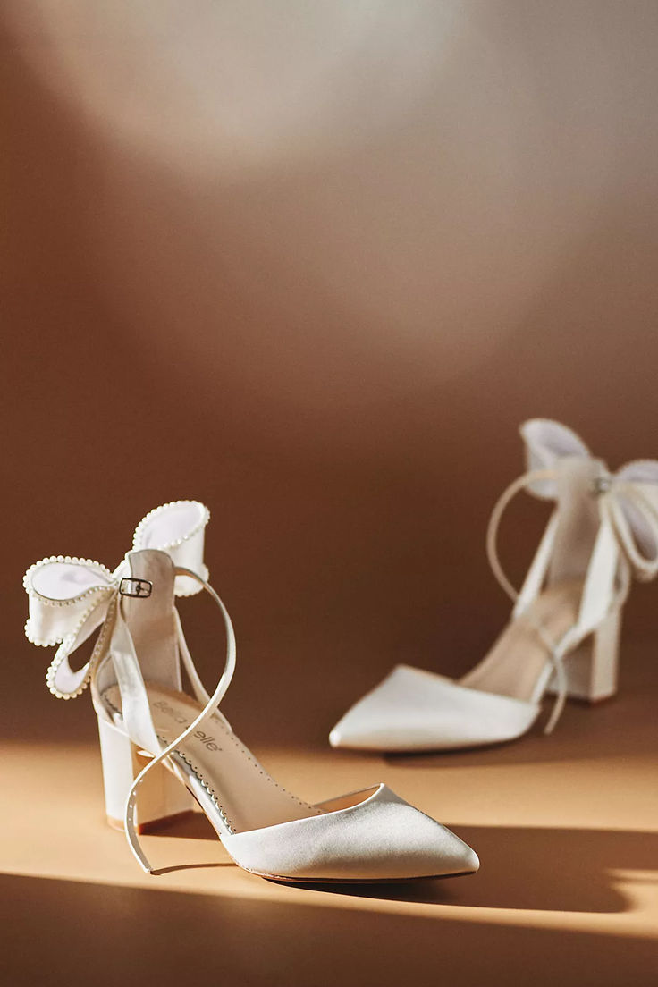 a pair of white high heeled shoes with bows