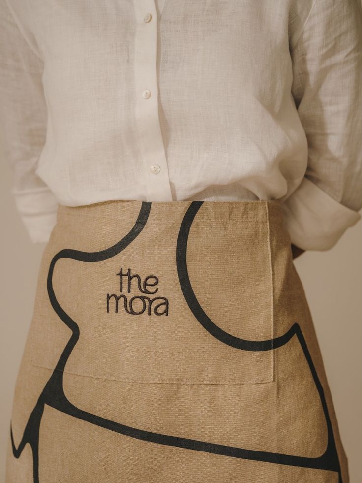 a woman wearing an apron with the word the moja on it's side