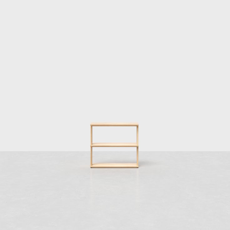 a small wooden shelf sitting on top of a white floor in front of a gray wall