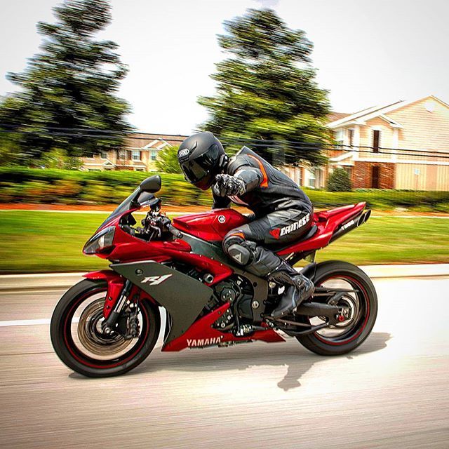 a man riding on the back of a red motorcycle