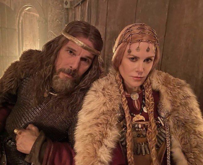 a man and woman dressed in medieval clothing standing next to each other with long hair