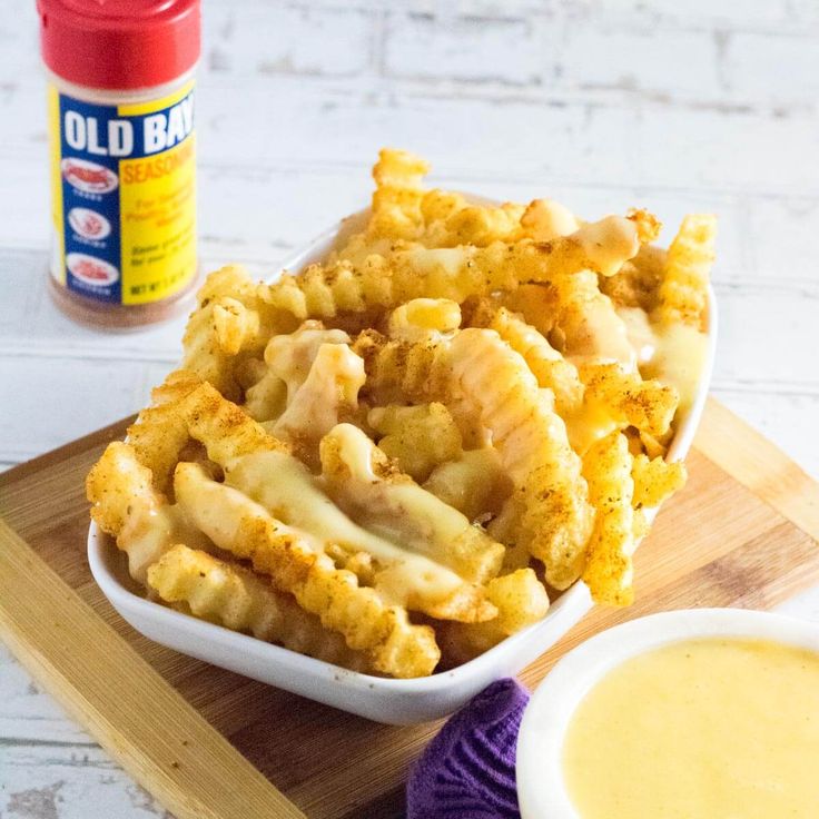 some food is in a white bowl on a cutting board next to a jar of mustard