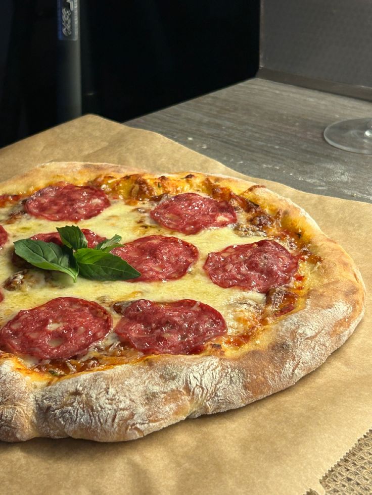 a pepperoni pizza sitting on top of a piece of wax paper